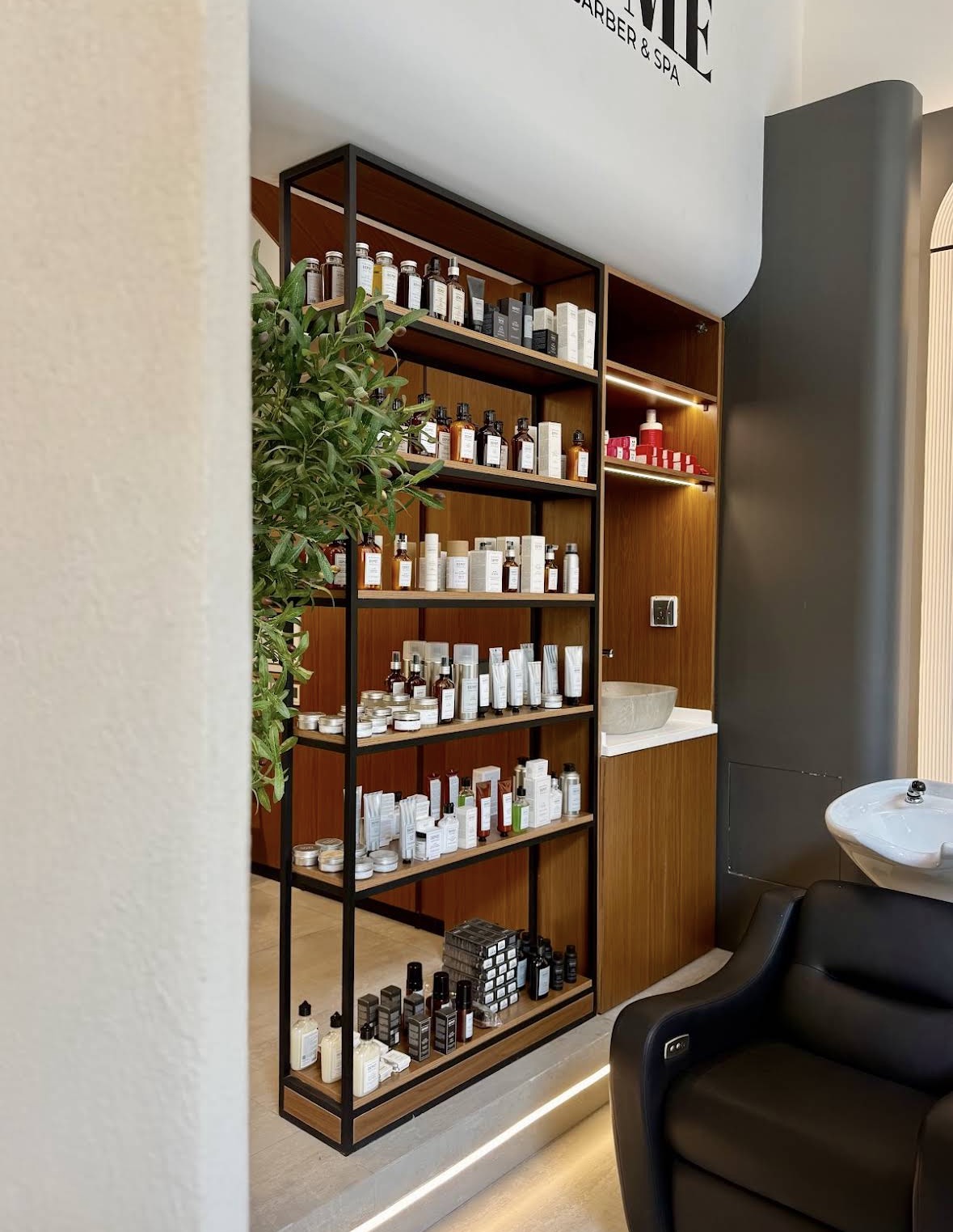 Grooming product display and wash basin beneath the Volume Barber & Spa sign