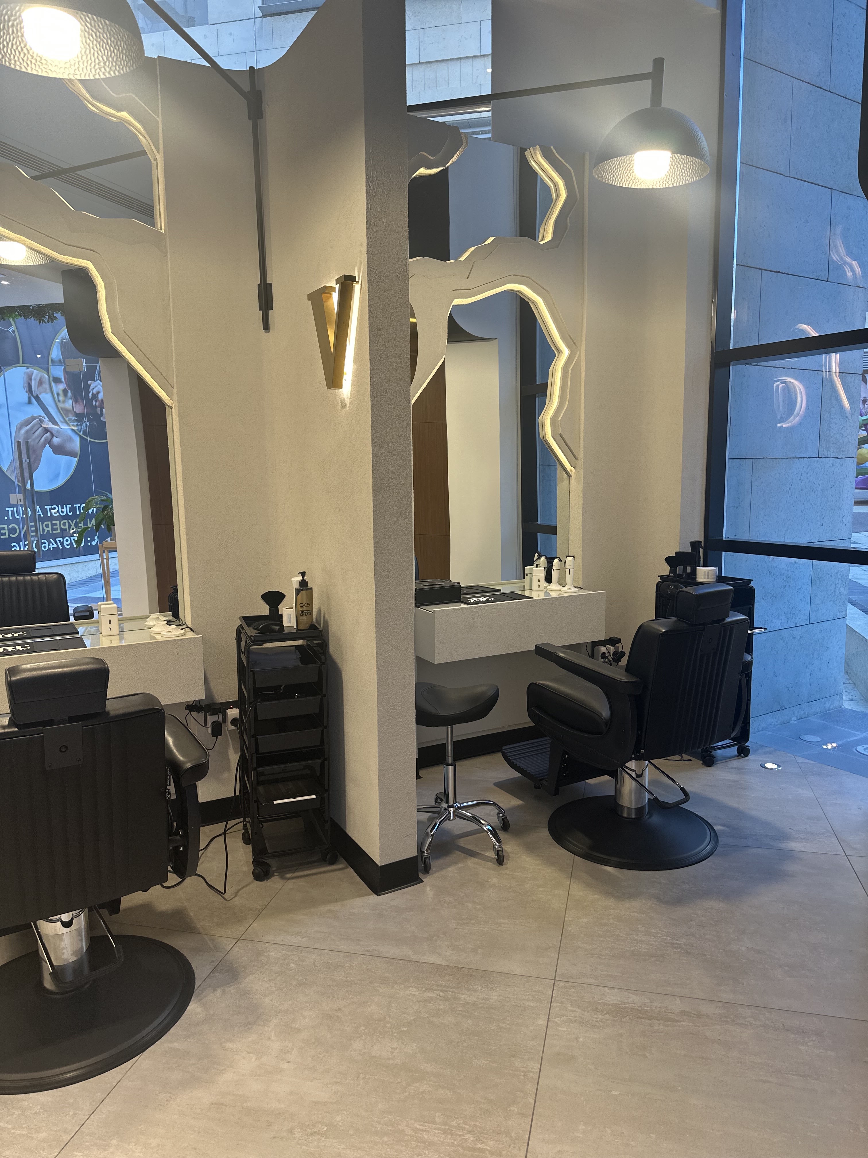 Volume Gentlemen Barber & Spa styling floor with sculptural mirrors and a backlit V wall sconce