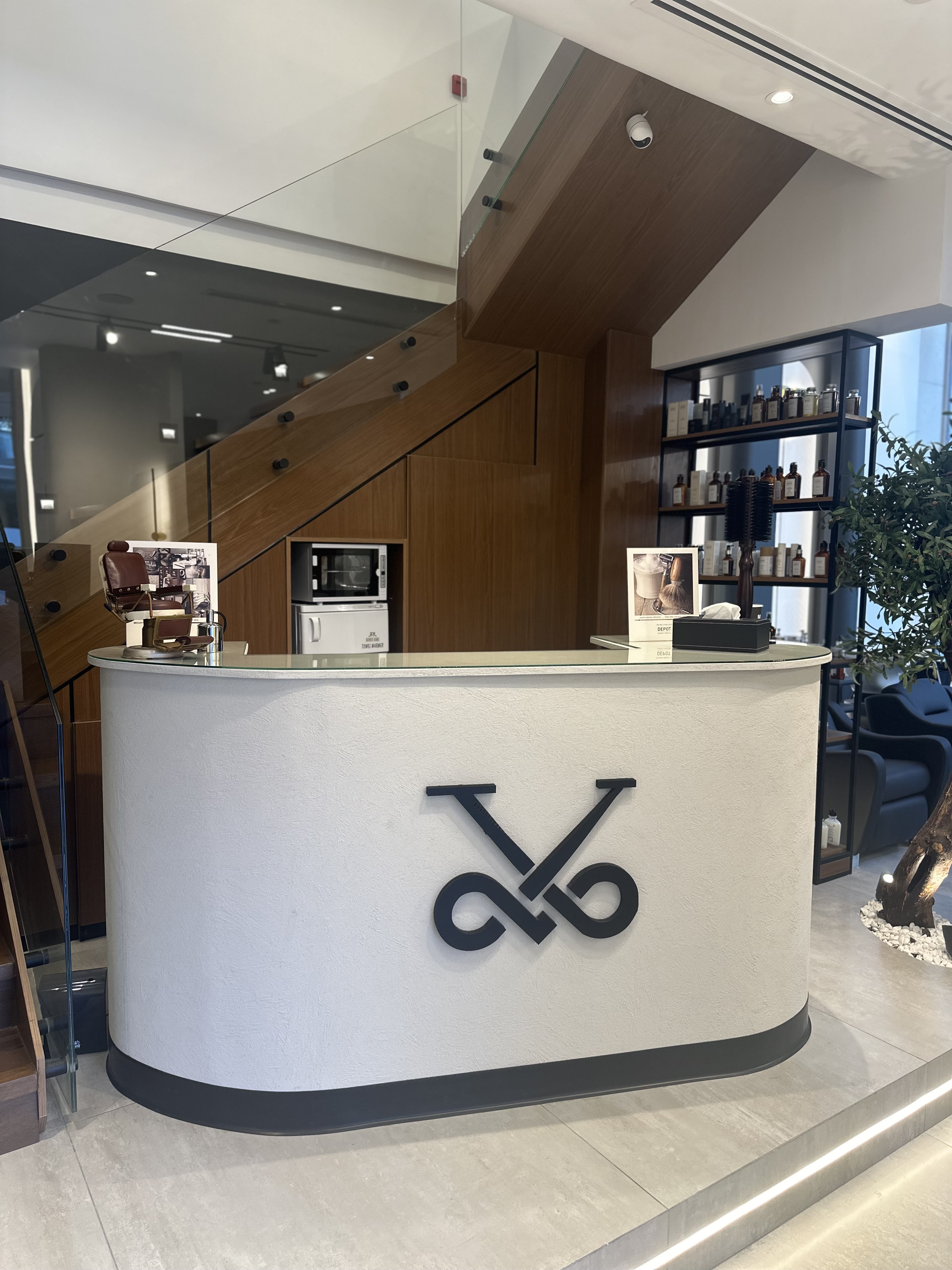 Curved plaster reception desk with the Volume scissor-and-razor logo